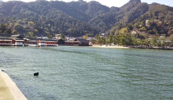 Distant view of Itsukushima Shrine at high tide, appearing surrounded by water
