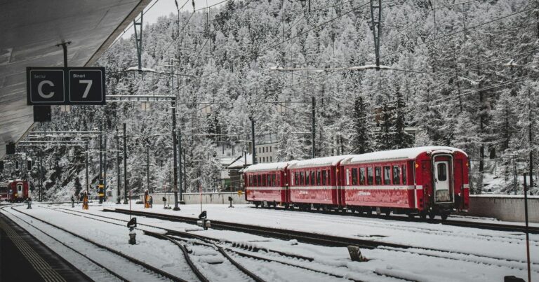 雪の駅ホームに停車する赤い列車の風景（なごり雪のイメージ）