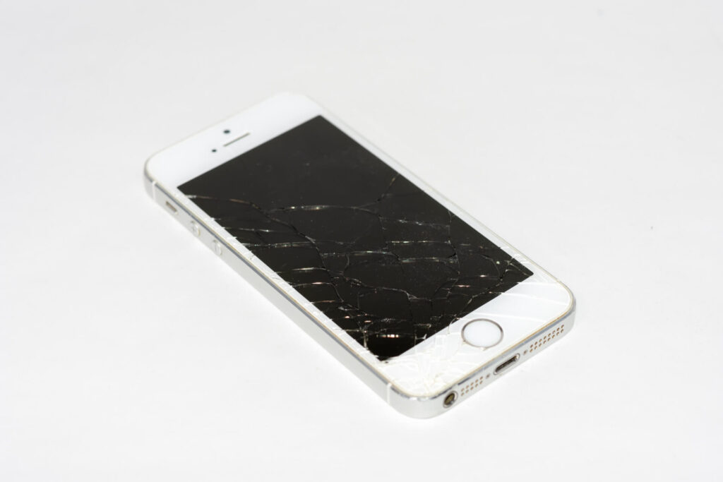 A smartphone with a visible cracked screen placed on a surface